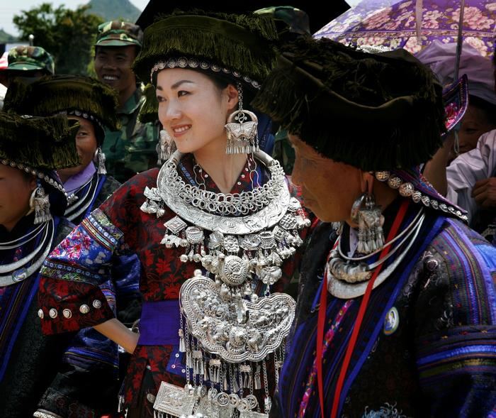 People wearing embroidered clothing and jewelry in a photograph labeled Hmong Black (Hmoob Dub)